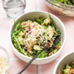 italian farro salad with arugula in white bowl with glass of water