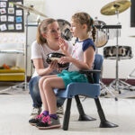 A child with autism sits in a Rifton compass chair to participate in music class