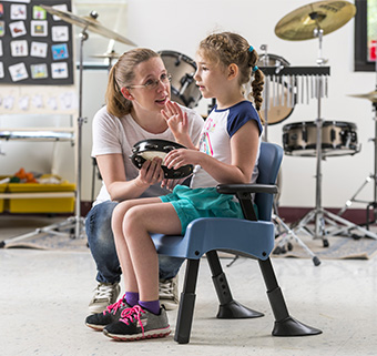 A child with autism sits in a Rifton compass chair to participate in music class