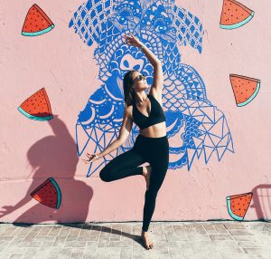 Harriet in tree pose in front of a mural with watermelon slices
