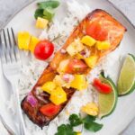 baked salmon with mango pineapple salsa over rice on a plate