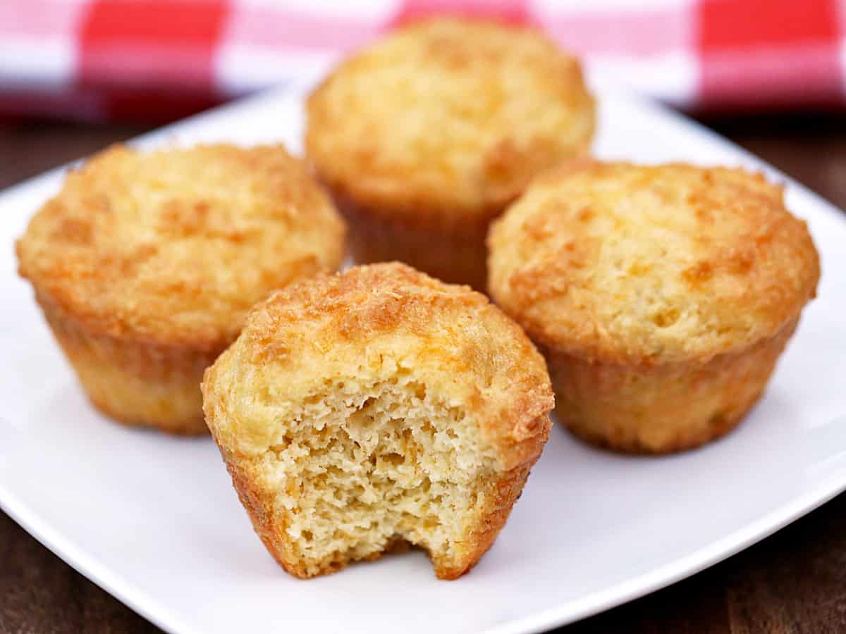 Four keto cheese muffins served on a white plate.