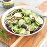 Cucumber Salad {Keto} in a white bowl on a cutting board