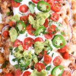 close up top down view of bbq chicken totchos with sour cream, tomatoes and guacamole