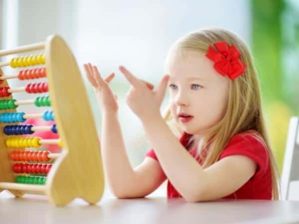 girl using a colourful abacus and counting on her fingers