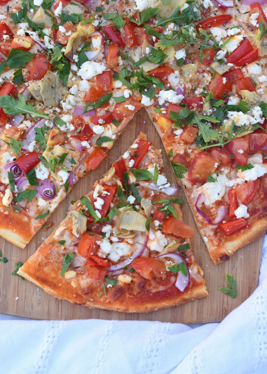 Greek Pizza is loaded with feta cheese, artichokes, tomatoes, red peppers, parsley, red onion and more for a flavor packed pizza ready in no time!