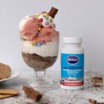 Ice cream sundae on a marble counter next to a tub of Milkaid lactase enzyme chewable tablets to treat lactose intolerance